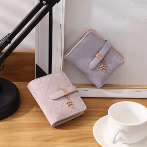 Detail of quilted leather card holders with leaf pendant and metal buckle closure