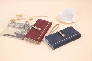 Detail view of burgundy and navy frosted long wallets with retro metal buckle and wrist strap