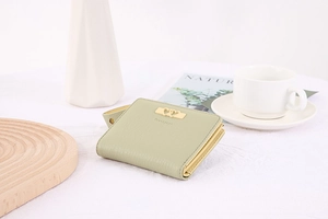 Close-up of light green bifold wallet with gold heart hardware and litchi texture