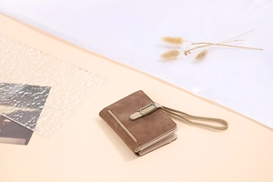 Close-up of vintage brown matte PU leather wallet with metal buckle and wrist strap