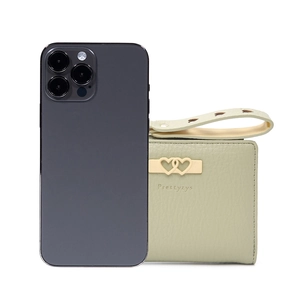 Short green leather wallet with heart buckle and hand strap next to phone for size comparison