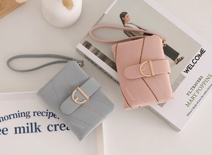 Detail of pink and dark grey quilted wallets with wrist straps on a white background