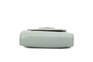 Detail view of the mint green leather wallet showing fine stitching and floral accent