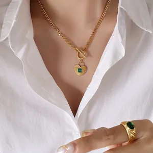 Gold OT buckle necklace with green heart pendant and matching stone ring on a model