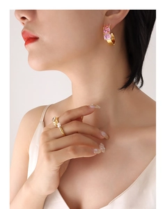 Detail of C-shaped gold hoop earrings with pink square zircon and pearl ring