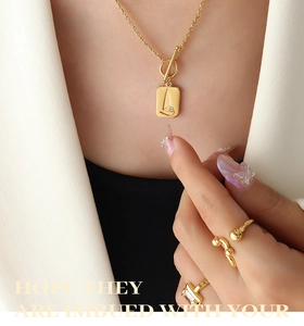 Close-up of 18K gold-plated OT buckle necklace with rectangular pendant and rings