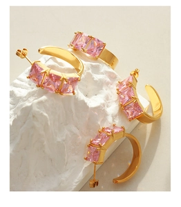 Detail of C-shaped gold earrings set with rectangular pink zirconias on stone