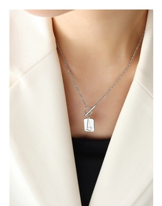 Detail of silver geometric rectangular pendant with abstract face engraving and OT toggle