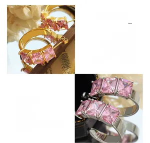 Detail of C-shaped earrings with pink zircon stones in gold and silver finishes