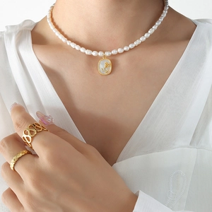 Collier perles baroques avec pendentif rose en relief et bagues dorées sur mannequin