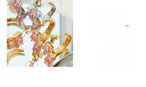 Macro shot of C-shaped earrings with pink square-cut gemstones on a reflective mirror