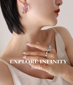 Detail shot of C-shaped silver earrings with pink square stones and pearl ring on model