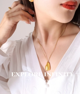 Détail du collier avec pendentif goutte d'eau irrégulière et bagues dorées sur modèle