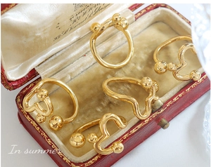 Detail of five gold wavy rings with metallic beads on a velvet jewelry box surface