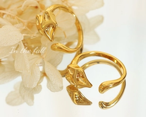Detailed view of fox-shaped gold rings set against autumn flowers with reflections