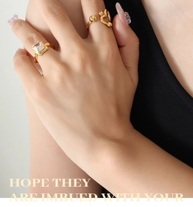 Detailed view of layered gold rings with a large square zircon and heart cutout
