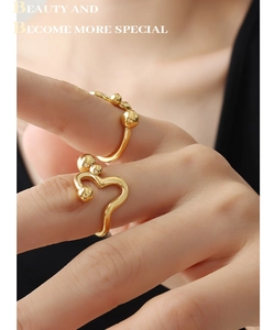 Detail of adjustable gold rings with abstract heart curves and polished bead accents