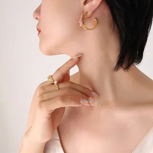 Elegant C-shaped gold hoop earrings with sparkling pink gemstones and matching rings