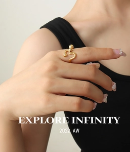 Close-up of golden curved open ring with spherical bead detail worn on finger