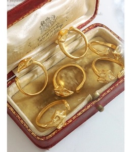 Detail of five adjustable gold fox head rings displayed in a red vintage jewelry box