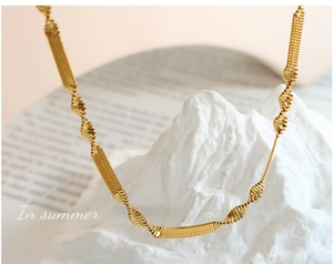 Detailed view of gold plated hip hop chain necklace with geometric twist links on white stone