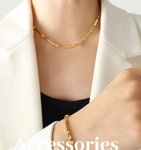 Close-up of golden blade chain necklace and bracelet set worn on a model's neck