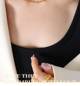 Macro shot of gold-plated ribbed ring and delicate chain necklace on model