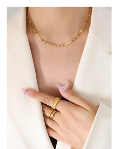 Detail of hip hop style gold plated titanium necklace and rings set on a model