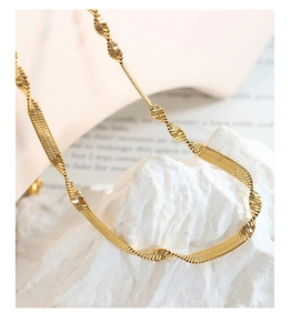 Macro shot of twisted gold blade chain necklace with metallic luster on stone