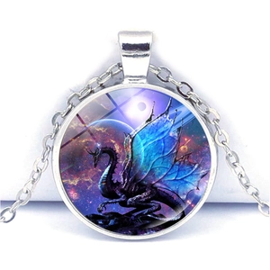 Vue macro du pendentif cabochon en verre avec dragon bleu et fond de nébuleuse colorée