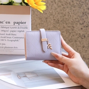 Detail of lavender quilted wallet with a golden leaf charm and folding buckle