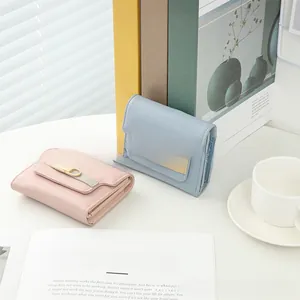 Close-up of pink and blue trifold wallets with gold buckles in soft natural light