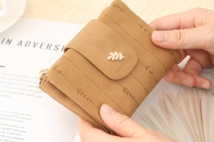 Detailed close-up of brown vintage wallet featuring gold leaf charm and textured leaf pattern