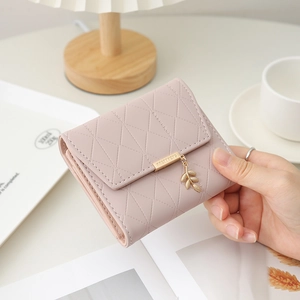 Détail d'un portefeuille rose en cuir PU avec pendentif feuille et finitions dorées