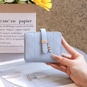 Close-up of light blue quilted leather wallet with leaf pendant and RFID blocking