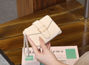 Close-up of cream PU leather wallet featuring V-shaped stitching and gold clasp with wristlet