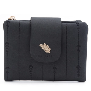 Detail of black short wallet with vertical quilting, leaf charm, and gold hardware