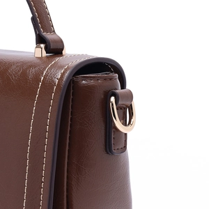 Détail d'un sac bandoulière en cuir marron avec anneau en D doré et coutures beiges