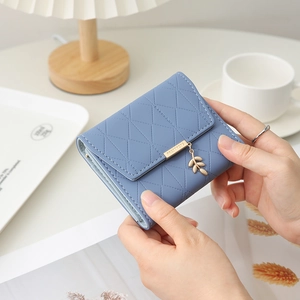 Gros plan d'un portefeuille matelassé bleu clair avec pendentif feuille et fermoir métal