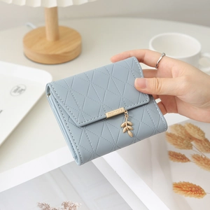 Détail du portefeuille bleu clair en similicuir avec motif matelassé et pendentif feuille