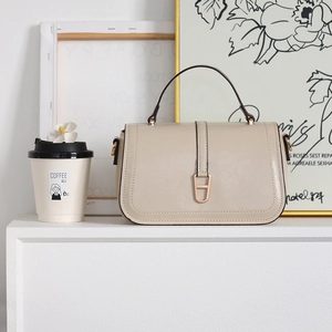 Détail d'un sac à main beige en cuir avec fermeture à rabat et boucle dorée élégante