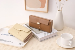 Detail of long and medium leather wallets with heart pendants in beige and tan colors
