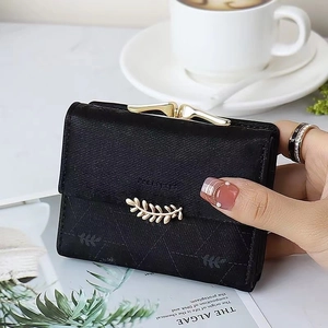 Close-up of black matte wallet with leaf embossing and golden buckle held by hand