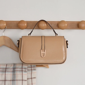 Détail du sac bandoulière en cuir PU beige avec boucle fer à cheval sur crochet en bois