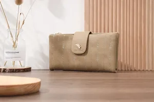 Detail of khaki long wallet featuring leaf-shaped metal clasp and vertical leaf embroidery
