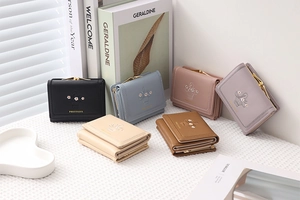 Detailed view of floral embroidery and metallic kiss-lock on faux leather trifold wallets
