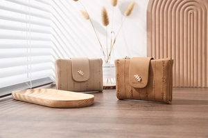 Detail of short wallets with leaf embroidery and metal snap closure in warm natural light