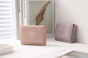Close-up of trifold PU leather wallets with daisy embroidery in pink and purple colors