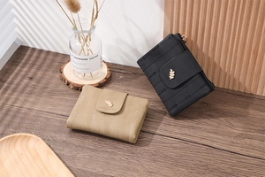 Close-up of khaki and black leaf buckle wallets with elegant stitching on wooden surface