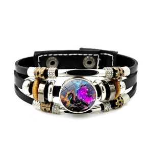 Macro shot of punk leather bracelet showing beads and a glass dome with a dragon motif